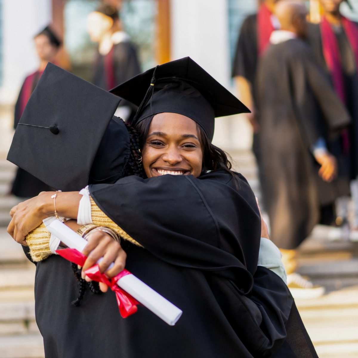 Young student is embracing each other after the graduating ceremony Happy young student is embracing a friend during the graduating ceremony outside the University