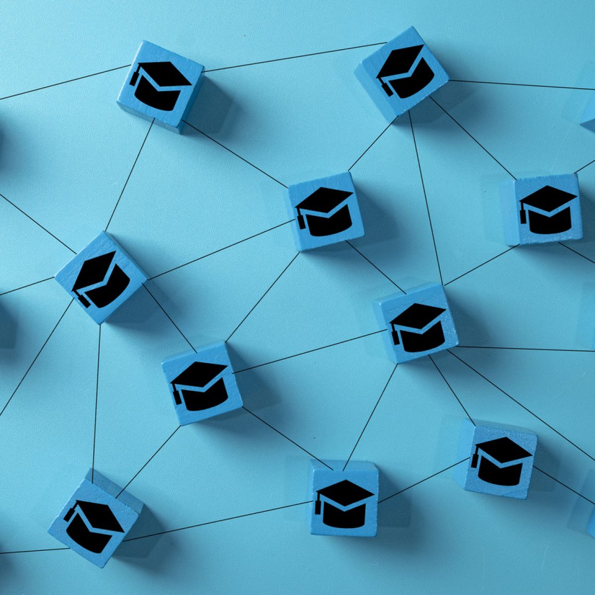 E-learning and online education concept. A network of interconnected blocks with graduation cap icons, symbolizing distance learning, virtual universities, and digital knowledge sharing platforms.